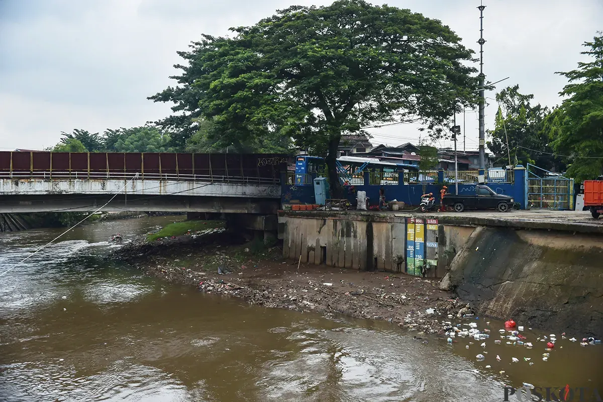 Alat berat membersihkan tumpukan sampah yang mengambang serta endapan sedimentasi di area Pintu Air Manggarai, Jakarta, Jumat, 10 Januari 2024. (Sumber: Poskota/ Bilal Nugraha Ginanjar)