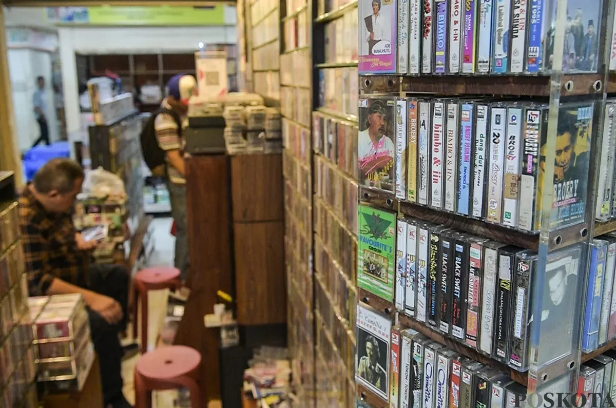 Pengunjung sekaligus penikmat koleksi barang lawas, melihat dan menilik kaset pita yang jaya pada era 80 hingga 90-an di satu di antara lapak penjual kaset di Blok M Square, Jakarta, Senin, 20 Januari 2025. (Sumber: Poskoata/ Bilal Nugraha Ginanjar)