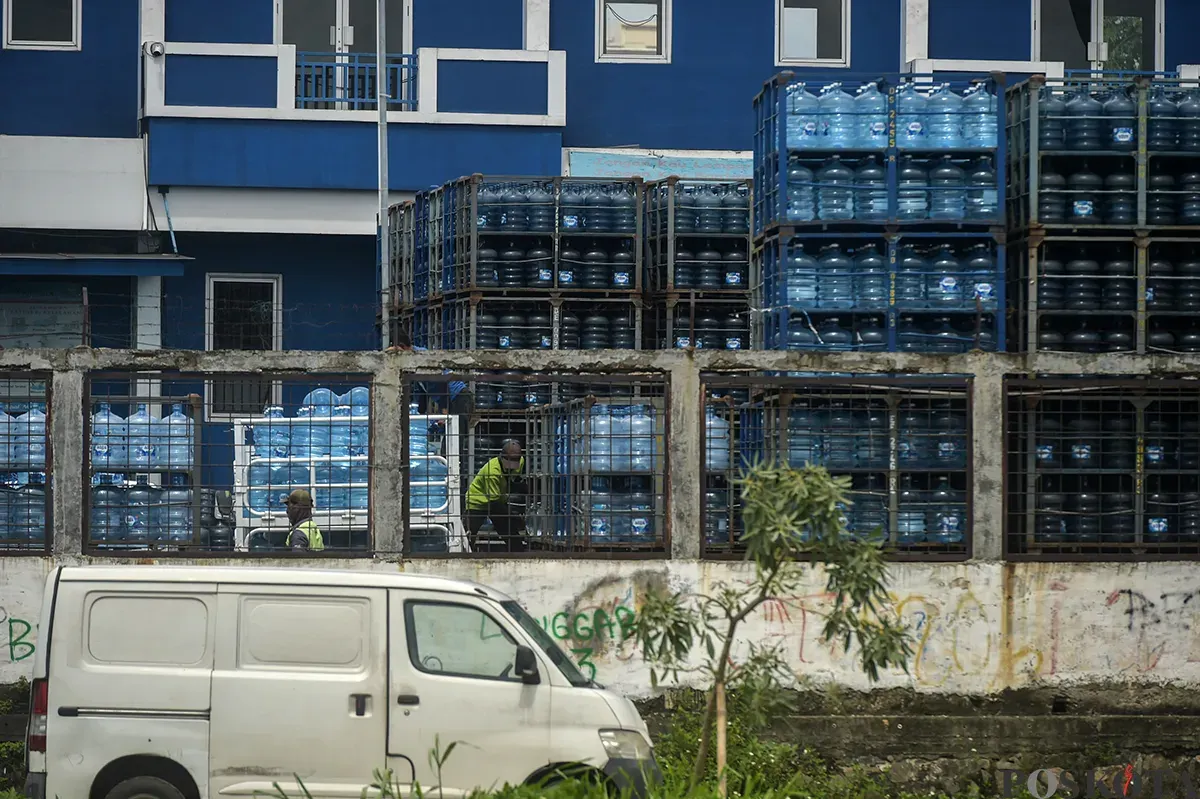 Pekerja memindahkan kemasan galon air mineral dengan alat berat di salah satu distributor air kemasan di kawasan depo air galon, Rawajati, Jakarta Selatan, Jum'at, 24 Januari 2025. (Sumber: Poskota/Bilal Nugraha Ginanjar)