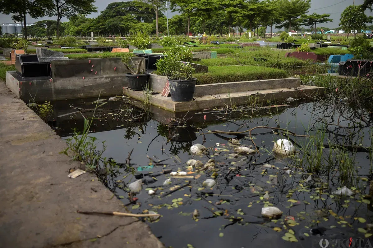 Warga berdoa di makam kerabat yang terendam air di Tempat Pemakaman Umum (TPU) Semper, Cilincing, Jakarta Utara, Jumat, 24 Januari, 2025. (Sumber: Poskota/Bilal Nugraha Ginanjar)