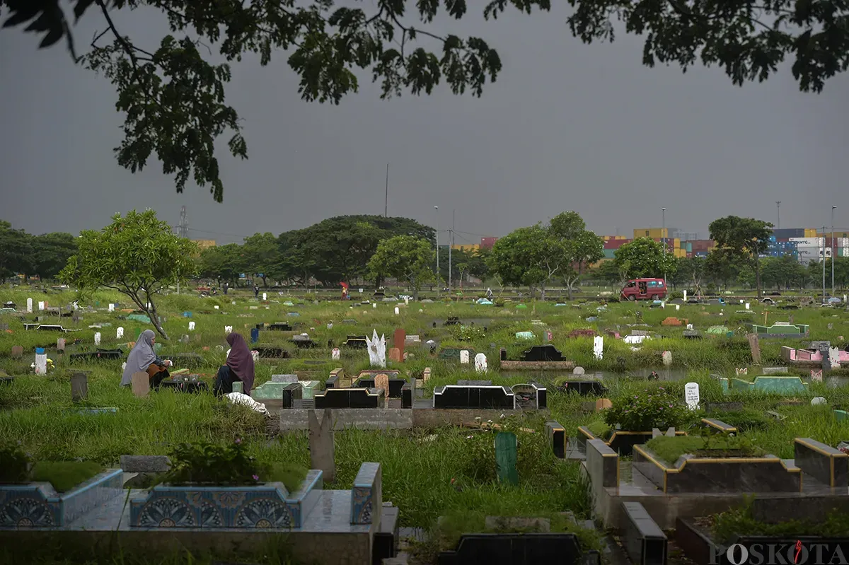Warga berdoa di makam kerabat yang terendam air di Tempat Pemakaman Umum (TPU) Semper, Cilincing, Jakarta Utara, Jumat, 24 Januari, 2025. (Sumber: Poskota/Bilal Nugraha Ginanjar)