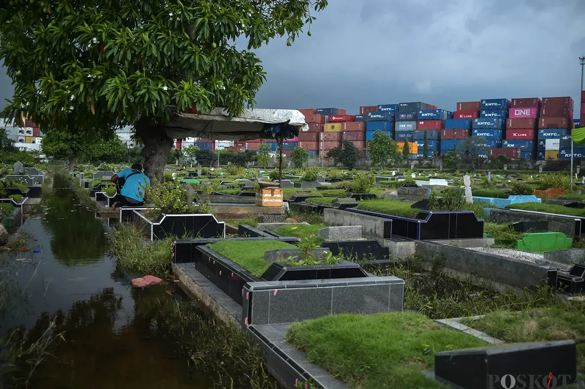 Warga berdoa di makam kerabat yang terendam air di Tempat Pemakaman Umum (TPU) Semper, Cilincing, Jakarta Utara, Jumat, 24 Januari, 2025. (Sumber: Poskota/Bilal Nugraha Ginanjar)