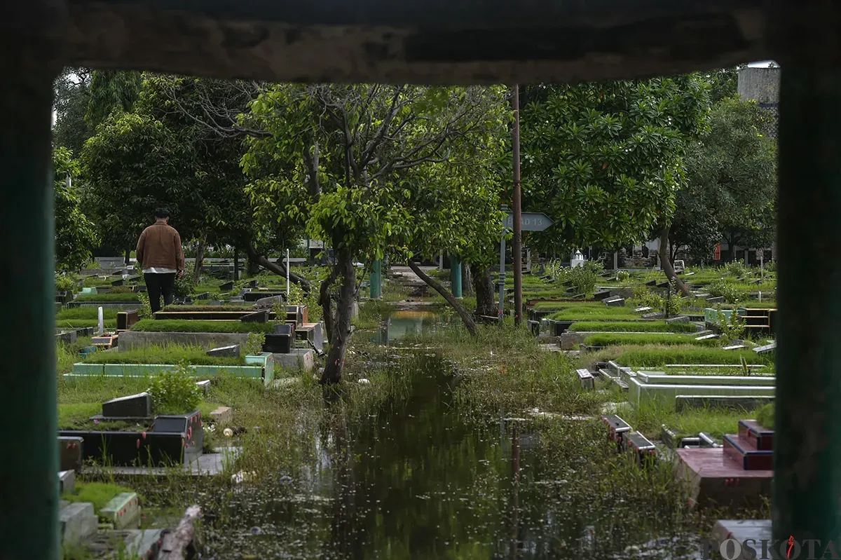 Warga berdoa di makam kerabat yang terendam air di Tempat Pemakaman Umum (TPU) Semper, Cilincing, Jakarta Utara, Jumat, 24 Januari, 2025. (Sumber: Poskota/Bilal Nugraha Ginanjar)