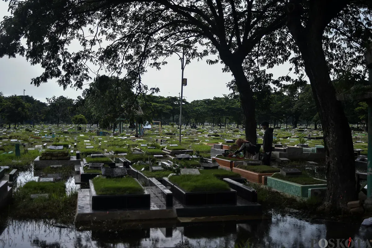 Warga berdoa di makam kerabat yang terendam air di Tempat Pemakaman Umum (TPU) Semper, Cilincing, Jakarta Utara, Jumat, 24 Januari, 2025. (Sumber: Poskota/Bilal Nugraha Ginanjar)