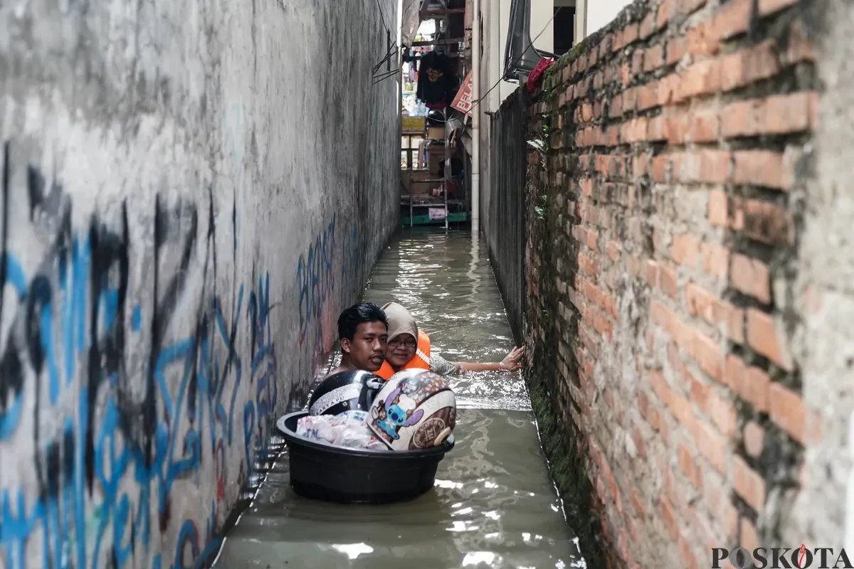 Warga berjalan melintasi banjir di Jalan Pirus, Bidara Cina, Jatinegara, Jakarta Timur, Minggu, 8 Juli 2025. (Sumber: Poskota/Bilal Nugraha Ginanjar)