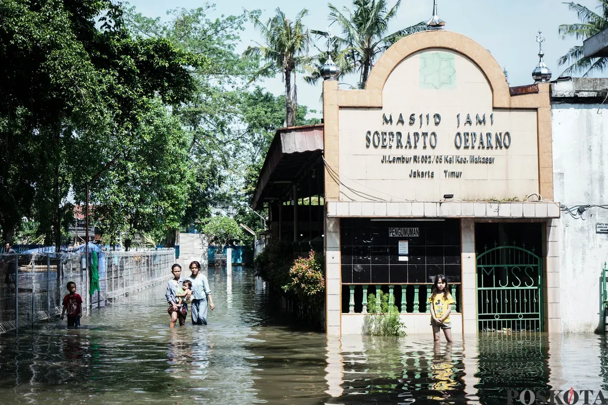 Warga berjalan melintasi banjir di Kampung Makasar, Jakarta Timur, Senin, 7 Juli 2025. (Sumber: Poskota/Bilal Nugraha Ginanjar)