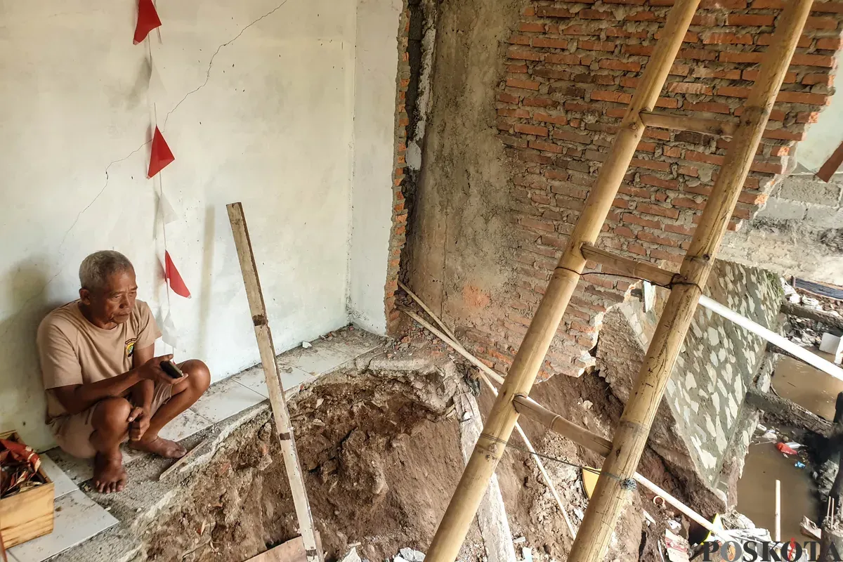Warga melihat kondisi rumahnya yang mengalami longsor di bantaran Sungai Ciliwung di Jalan Slamet Riyadi I, Kebon Manggis, Matraman, Jakarta Timur, Kamis, 10 Juli 2025. (Sumber: Poskota/Bilal Nugraha Ginanjar)