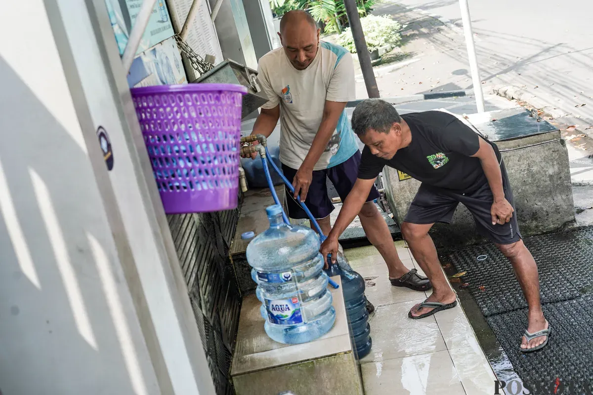 Warga mengisi botol air galon di depot air minum gratis di Jalan Rawamangun Muka Selatan, Jakarta Timur, Selasa, 15 Juli 2025. (Sumber: Poskota/Bilal Nugraha Ginanjar)