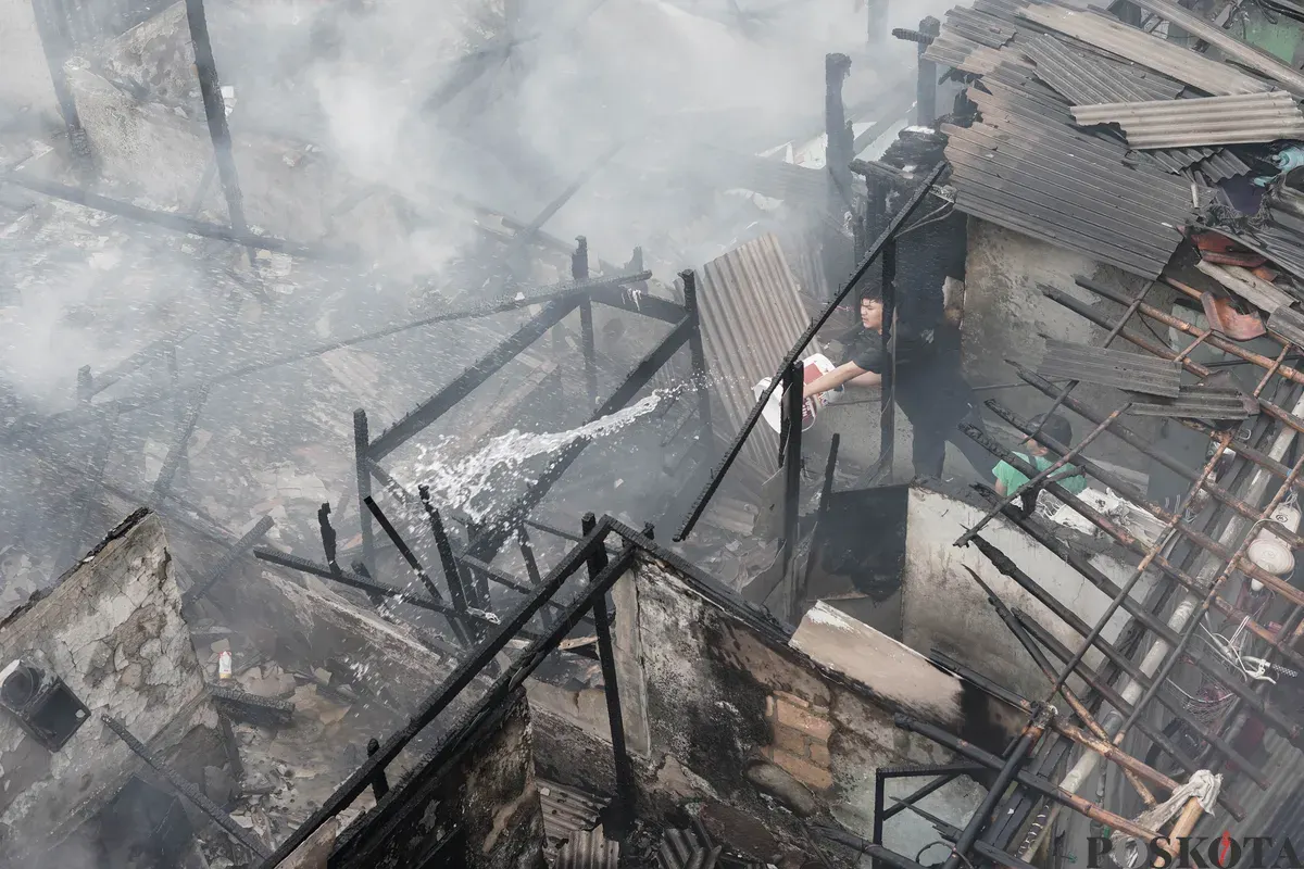 Warga memadamkan api yang membakar pemukiman padat penduduk di kawasan Grogol Utara, Kebayoran Lama, Jakarta Selatan, Minggu, 20 Juli 2025. (Sumber: Poskota/Bilal Nugraha Ginanjar)