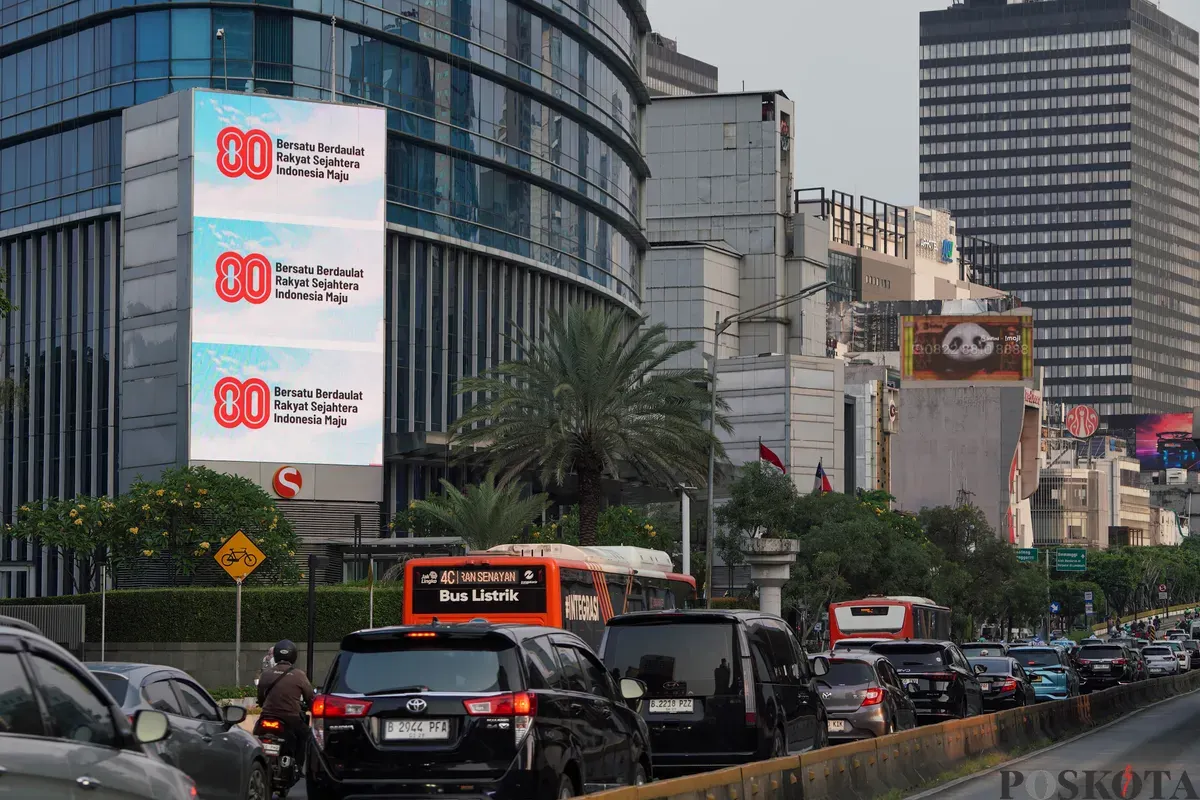 Sejumlah kendaraan melintas di dekat Videotron yang menampilkan logo HUT RI ke-80 di kawasan Jalan Sudirman, Jakarta, Kamis, 24 Juli 2025. (Sumber: Poskota/Bilal Nugraha Ginanjar)