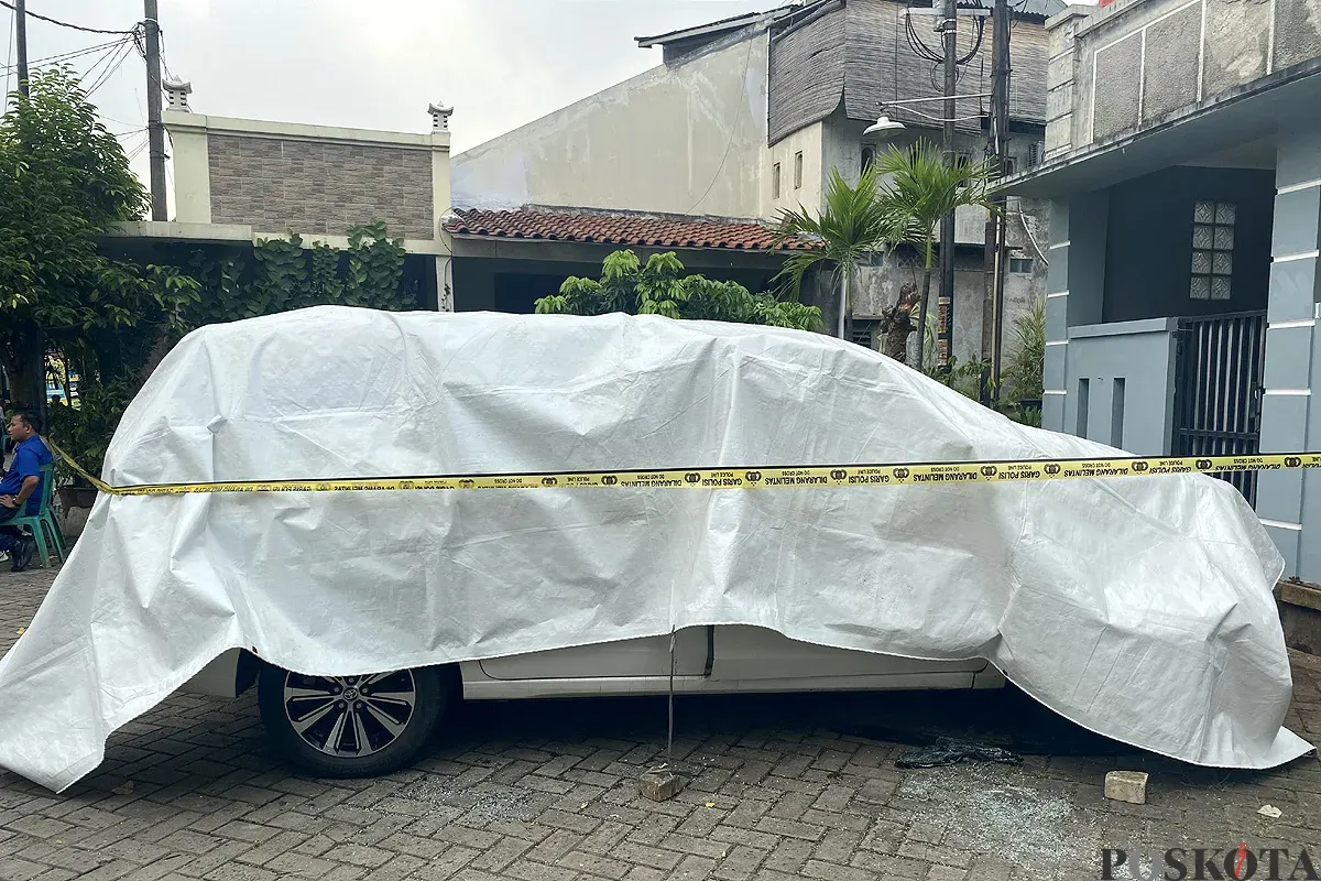 Kondisi mobil milik korban M yang tewas terbakar dipasang garis polisi di Perumahan Graha Pondok Kacang, Tangerang Selatan pada Selasa, 3 Juni 2025. (Sumber: POSKOTA | Foto: Primayanti)