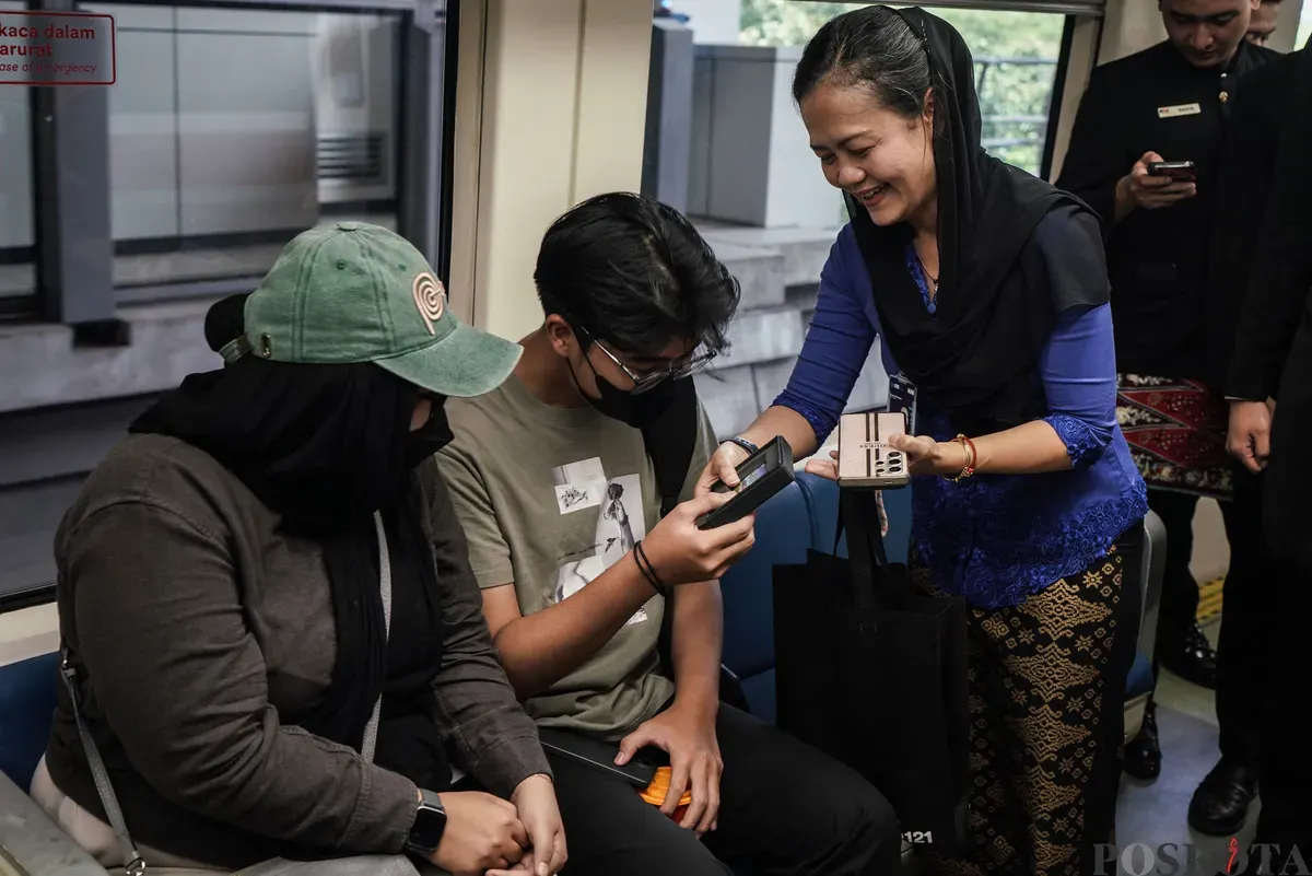 Vice President of Passanger Transport and Information Technology LRT Jabodebek Kristina Oktaviana membagikan KMT LRT Jabodebek edisi khusus Jakarta kepada penumpang di dalam gerbong LRT Jabodebek, Jakarta, Senin, 23 Juni 2025. (Sumber: Poskota/Bilal Nugraha Ginanjar)