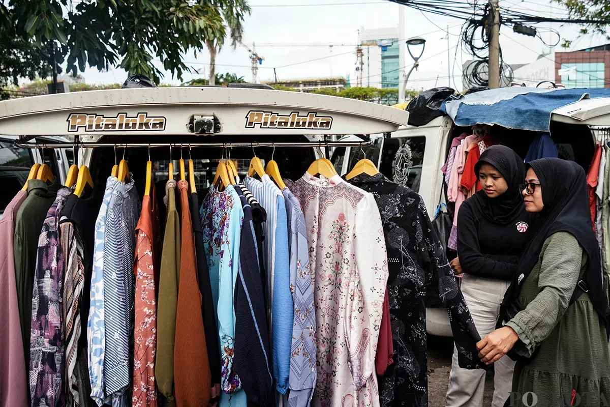 Pedagang melayani calon pembeli saat  memilih ragam busana lebaran di Pasar Tasik, Cideng, Jakarta Pusat, Kamis 20 Maret 2025. (Sumber: Poskoata/ Bilal Nugraha Ginanjar)