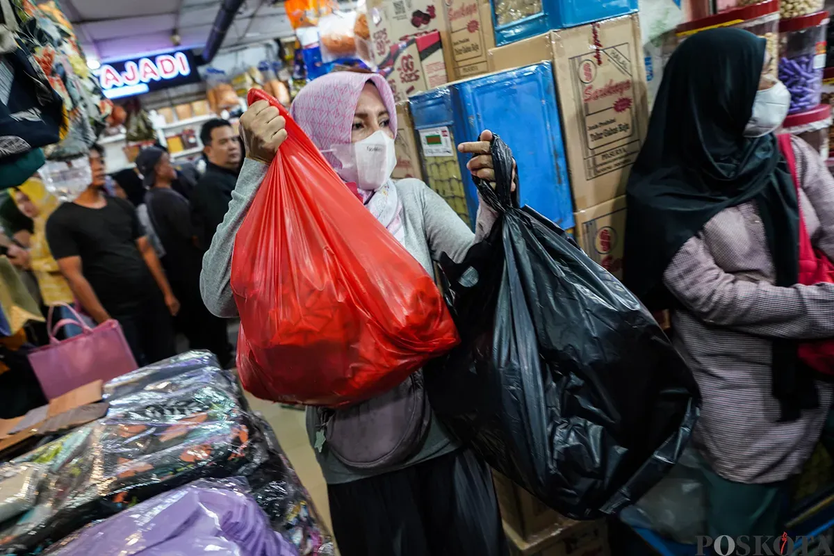 Pedagang melayani sejumlah pembeli aneka rasa kue kering yang ditawarkan di lapaknya di Pasar Jatinegara, Jakarta Timur, Jumat, 21 Maret 2025. (Sumber: Poskota/Bilal Nugraha Ginanjar)