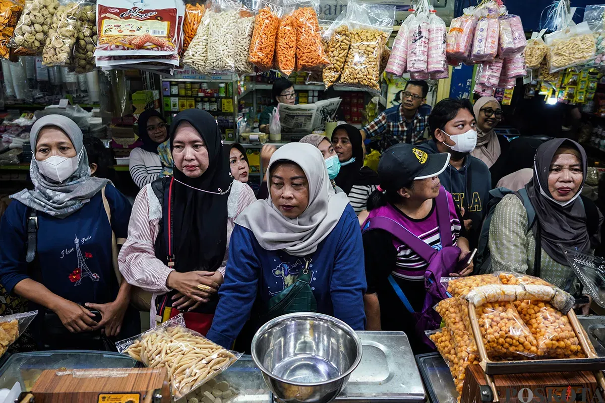 Pedagang melayani sejumlah pembeli aneka rasa kue kering yang ditawarkan di lapaknya di Pasar Jatinegara, Jakarta Timur, Jumat, 21 Maret 2025. (Sumber: Poskota/Bilal Nugraha Ginanjar)