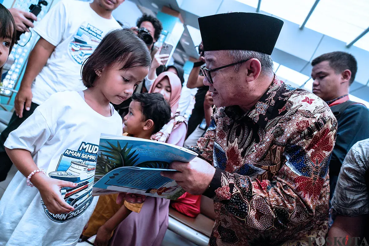 Menteri Pendidikan Dasar dan Menengah, Abdul Mu'ti, membagikan buku kepada anak-anak saat peluncuran program Mudik Asyik Baca Buku di Stasiun Pasar Senen, Jakarta, Rabu, 25 Maret 2025. (Sumber: Poskota/Bilal Nugraha Ginanjar)