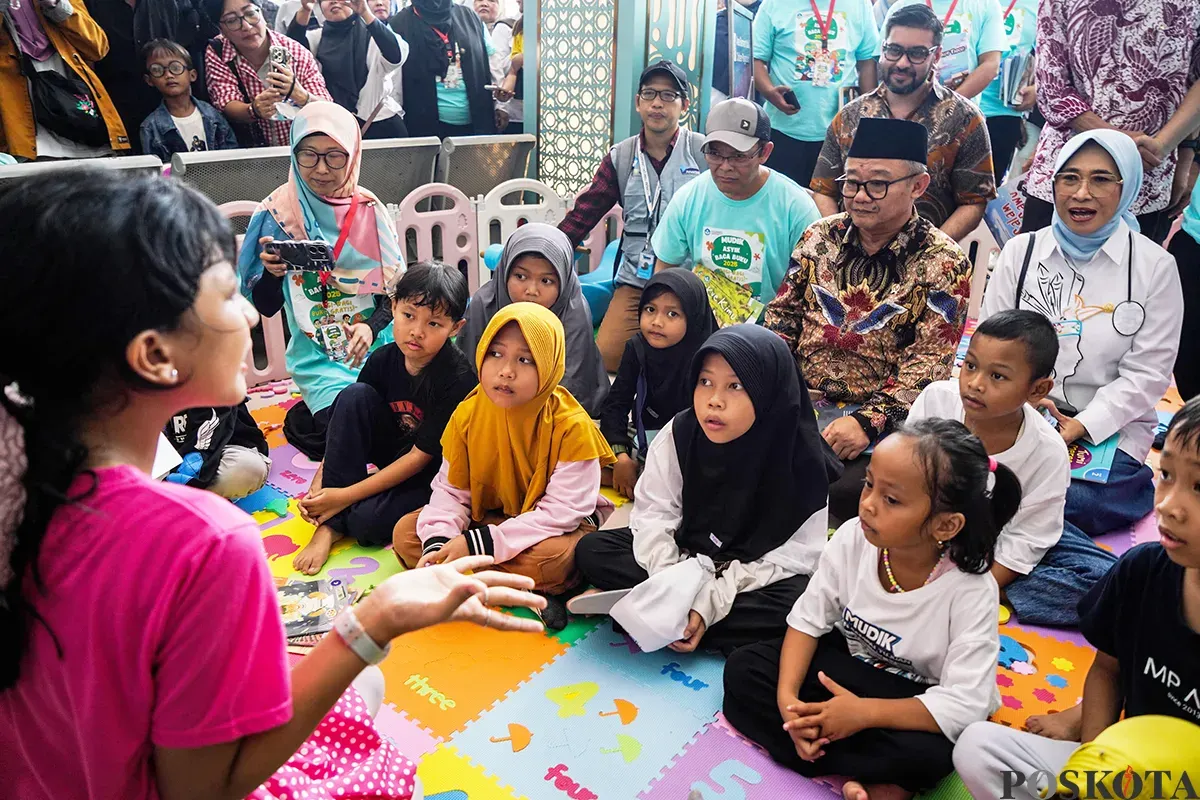 Menteri Pendidikan Dasar dan Menengah, Abdul Mu'ti, membagikan buku kepada anak-anak saat peluncuran program Mudik Asyik Baca Buku di Stasiun Pasar Senen, Jakarta, Rabu, 25 Maret 2025. (Sumber: Poskota/Bilal Nugraha Ginanjar)