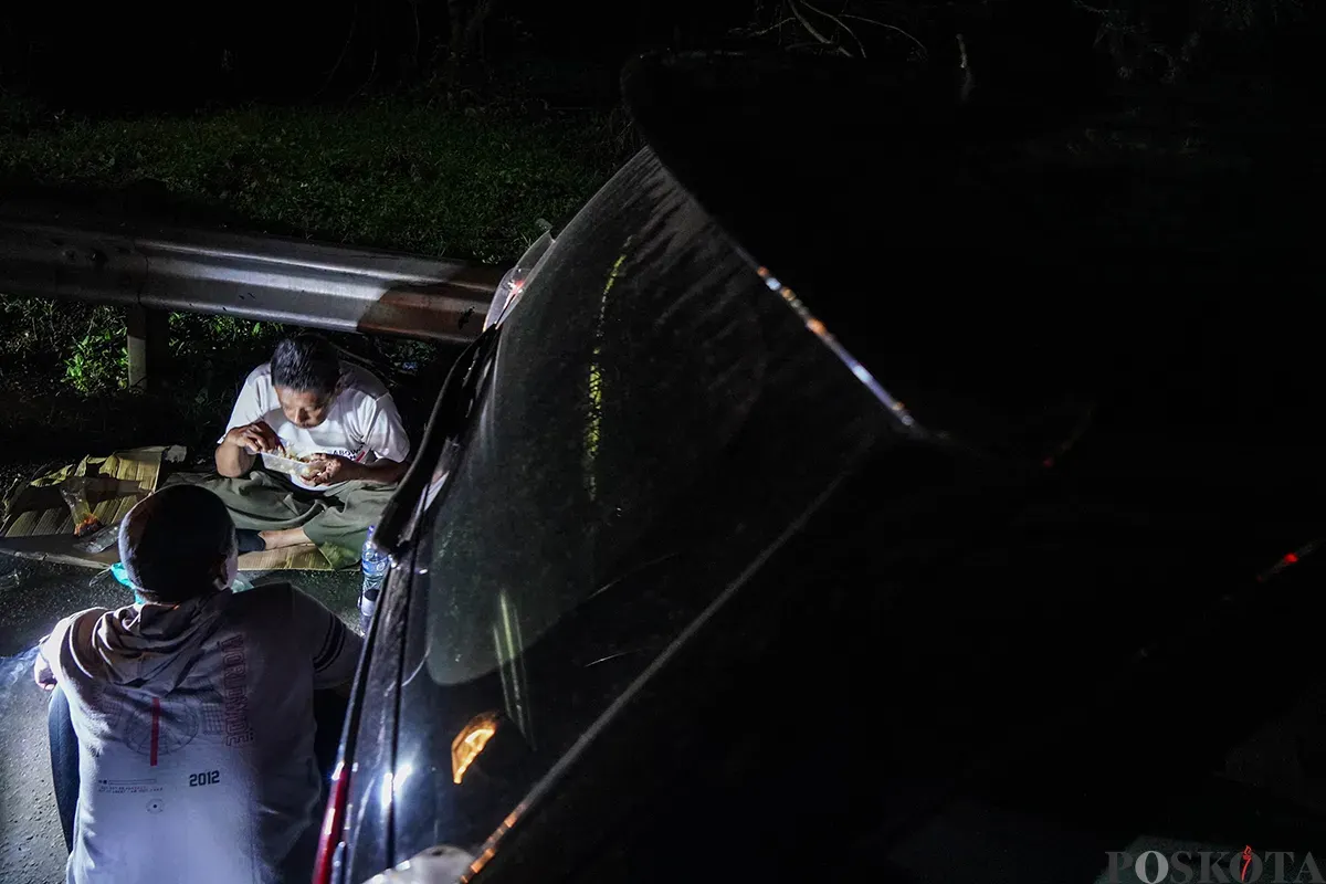 Pemudik beristirahat di pinggir jalan tol sambil melaksanakan sahur di area Tol Cikampek KM 28, Kabupaten Bekasi, Jawa Barat, 28 Maret 2025. (Sumber: Poskoata/ Bilal Nugraha Ginanjar)