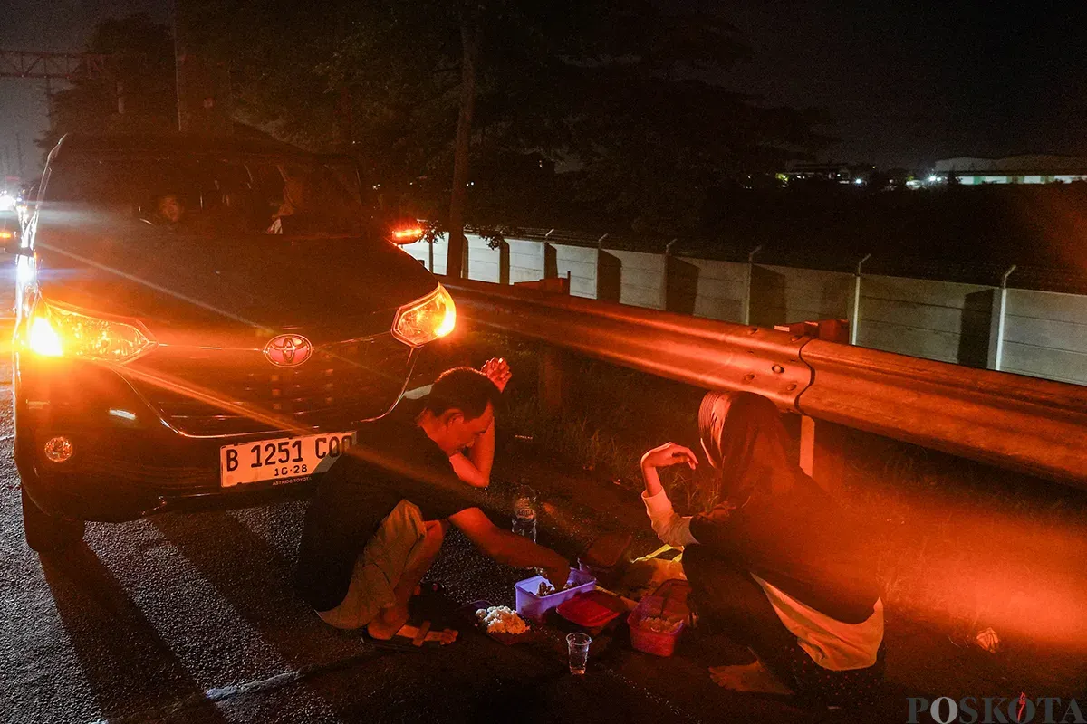 Pemudik beristirahat di pinggir jalan tol sambil melaksanakan sahur di area Tol Cikampek KM 28, Kabupaten Bekasi, Jawa Barat, 28 Maret 2025. (Sumber: Poskoata/ Bilal Nugraha Ginanjar)