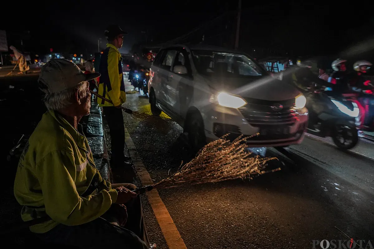 Sejumlah warga menggunakan sapu untuk mengambil uang sedekah yang dilempar para pengendara mudik di Jalur Pantura Sukra, Indramayu, Jawa Barat, Jumat, 28 Maret 2025. (Sumber: Poskoata/ Bilal Nugraha Ginanjar)