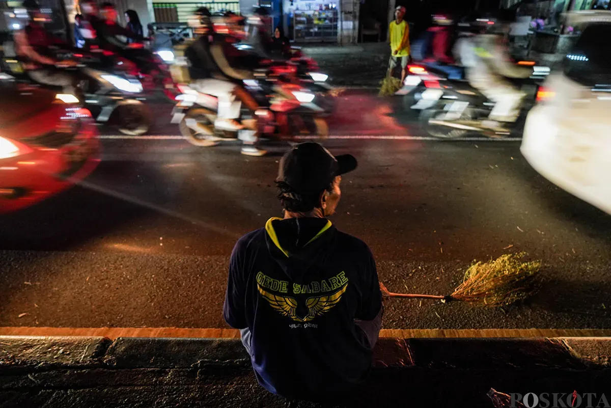 Sejumlah warga menggunakan sapu untuk mengambil uang sedekah yang dilempar para pengendara mudik di Jalur Pantura Sukra, Indramayu, Jawa Barat, Jumat, 28 Maret 2025. (Sumber: Poskoata/ Bilal Nugraha Ginanjar)