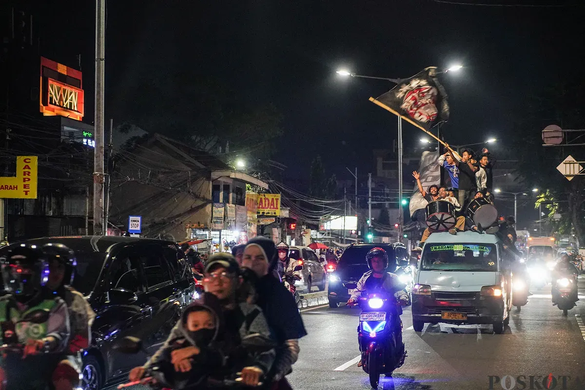 Warga menabuh bedug seraya menyalakan kembang api kerika melakukan pawai takbir keliling menggunakan kendaraan truk terbuka dan panggung warga di Jalan KH Mas Mansyur, Kebon Kacang, Tanah Abang, Jakarta, Minggu, 30 Maret 2025. (Sumber: Poskoata/ Bilal Nugraha Ginanjar)