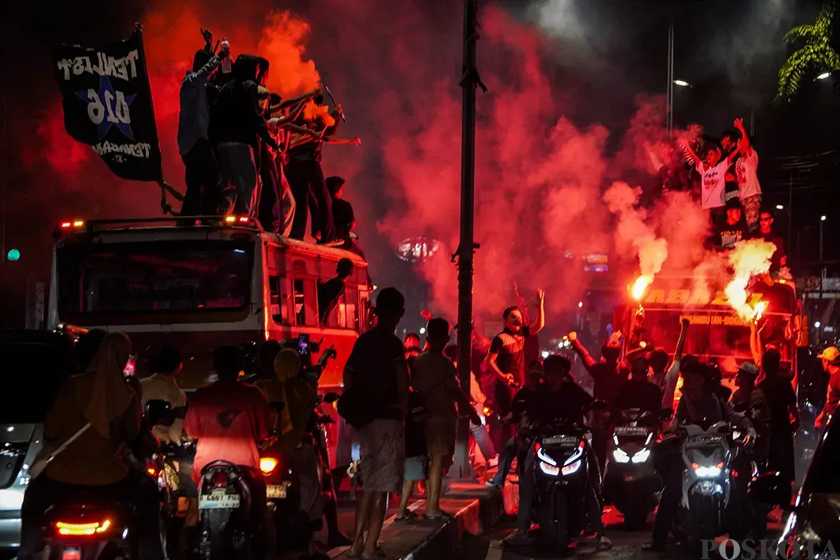 Warga menabuh bedug seraya menyalakan kembang api kerika melakukan pawai takbir keliling menggunakan kendaraan truk terbuka dan panggung warga di Jalan KH Mas Mansyur, Kebon Kacang, Tanah Abang, Jakarta, Minggu, 30 Maret 2025. (Sumber: Poskoata/ Bilal Nugraha Ginanjar)