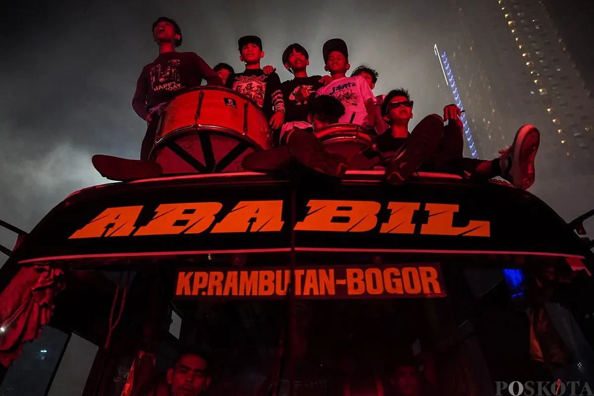 Warga menabuh bedug seraya menyalakan kembang api kerika melakukan pawai takbir keliling menggunakan kendaraan truk terbuka dan panggung warga di Jalan KH Mas Mansyur, Kebon Kacang, Tanah Abang, Jakarta, Minggu, 30 Maret 2025. (Sumber: Poskoata/ Bilal Nugraha Ginanjar)