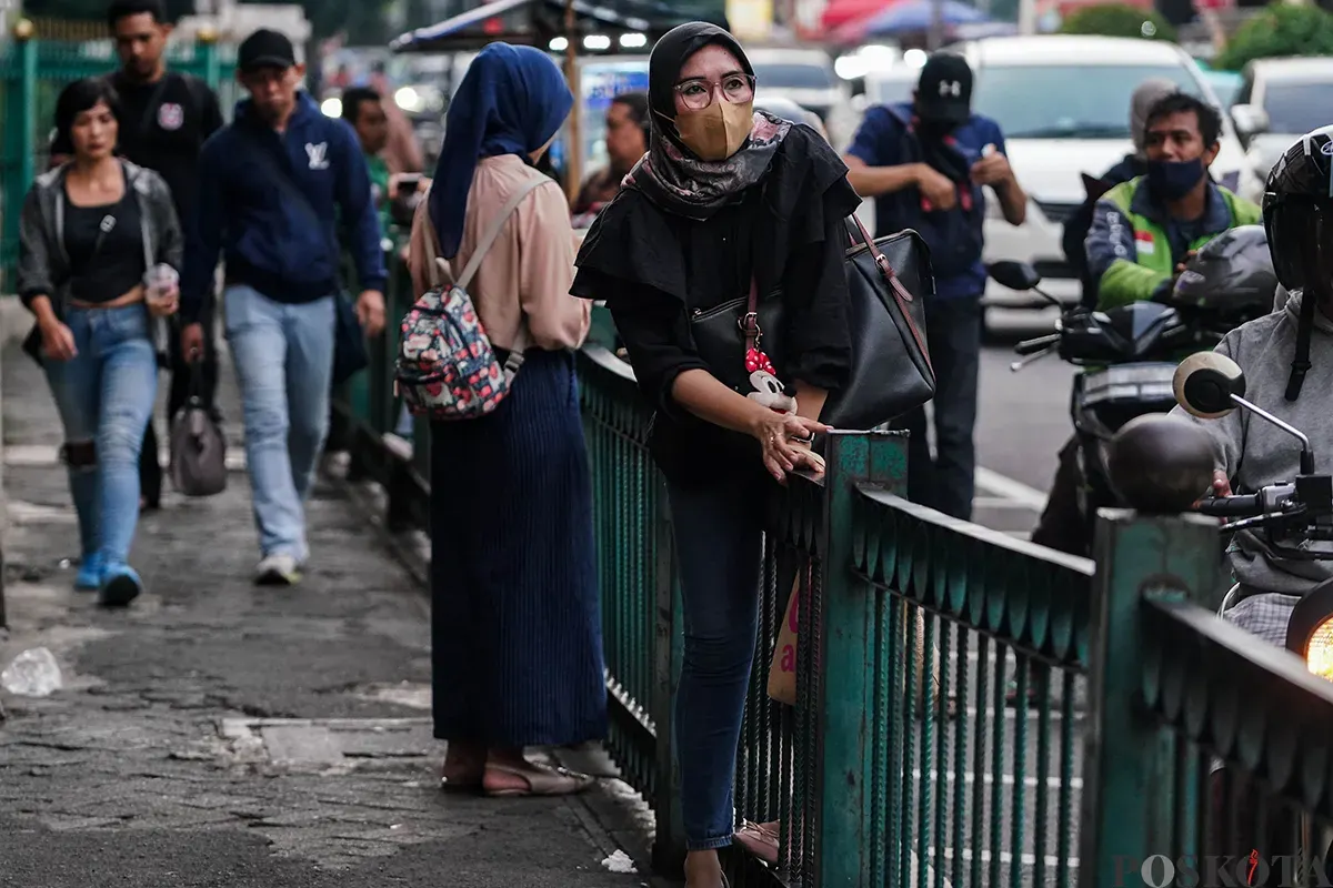 Sejumlah calon penumpang kereta api rela melompati pagar pembatas di depan Stasiun Cikini, Jakarta, Minggu, 4 Mei 2025. (Sumber: Poskota/Bilal Nugraha Ginanjar)