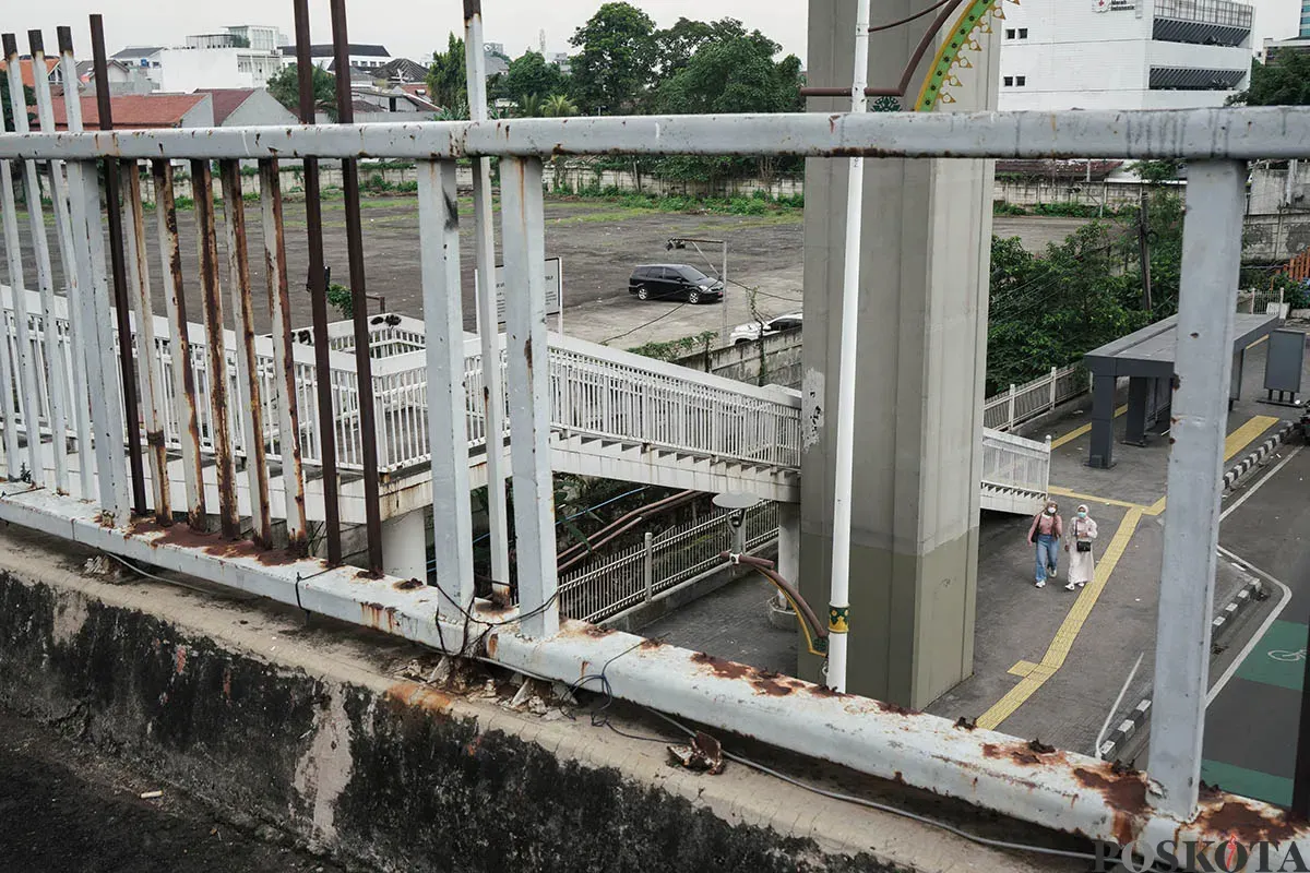 Warga berjalan diatas Jembatan Penyebrangan Orang (JPO) di depan Gedung Smesco, Jalan Gatot Subroto, Jakarta Selatan, tak terawat, Minggu, 25 Mei 2025. (Sumber: Poskota/Bilal Nugraha Ginanjar)