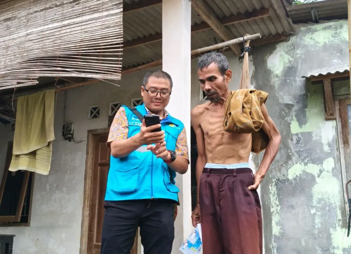 Petugas PLN UP3 Pondok Gede sedang membantu warga untuk memahami cara penggunaan SwaCam melalui PLN Mobile. (Sumber: Dok. PLN)