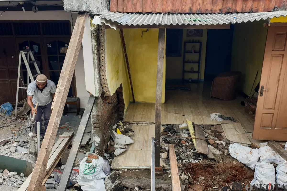 Warga membersihkan puing - puing rumahnya yang hancur akibat pergerakan tanah di Gang Sumur Jambu, Makasar, Jakarta Timur. (Sumber: Poskota/Bilal Nugraha Ginanjar)