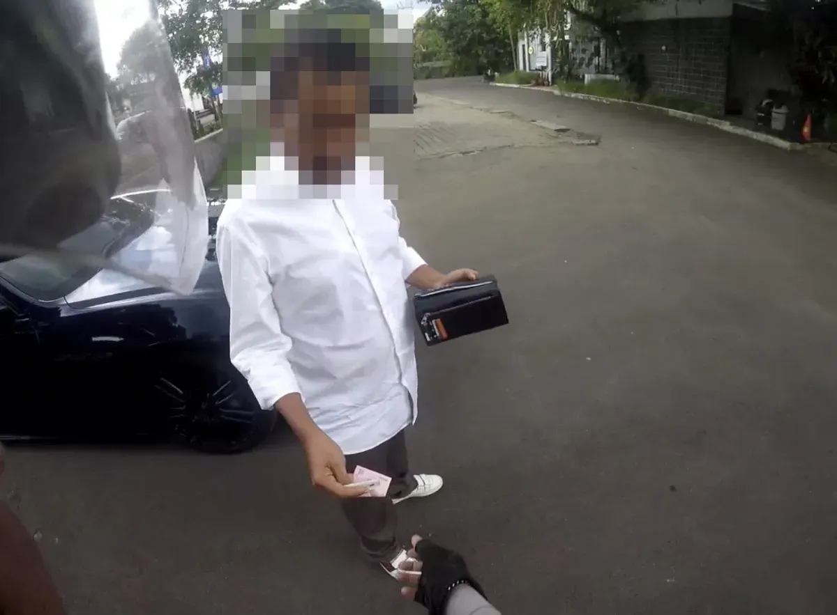 Tangkap layar seorang pria di Jalan Raya Puncak Bogor, berusaha menyuap anggota Satlantas saat ditilang.