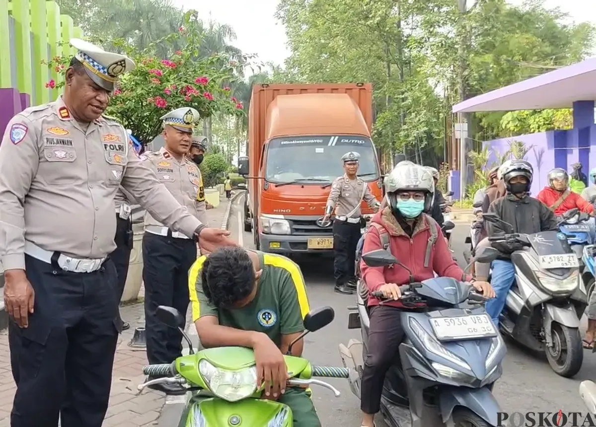 Petugas Satlantas Polresta Tangerang saat memberikan edukasi kepada pelajar yang tidak menggunakan helm di Lampu Merah Tigaraksa. (Sumber: Poskota/Veronica Prasetio)