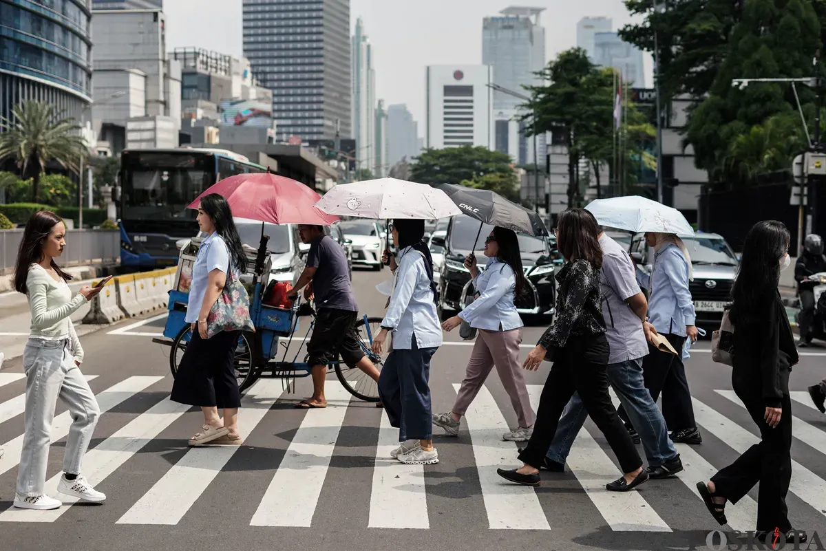 Warga berjalan di tengah cuaca terik di Jalan Jenderal Sudirman, Jakarta, Kamis, 16 Oktober 2025. (Sumber: Poskota/Bilal Nugraha Ginanjar)