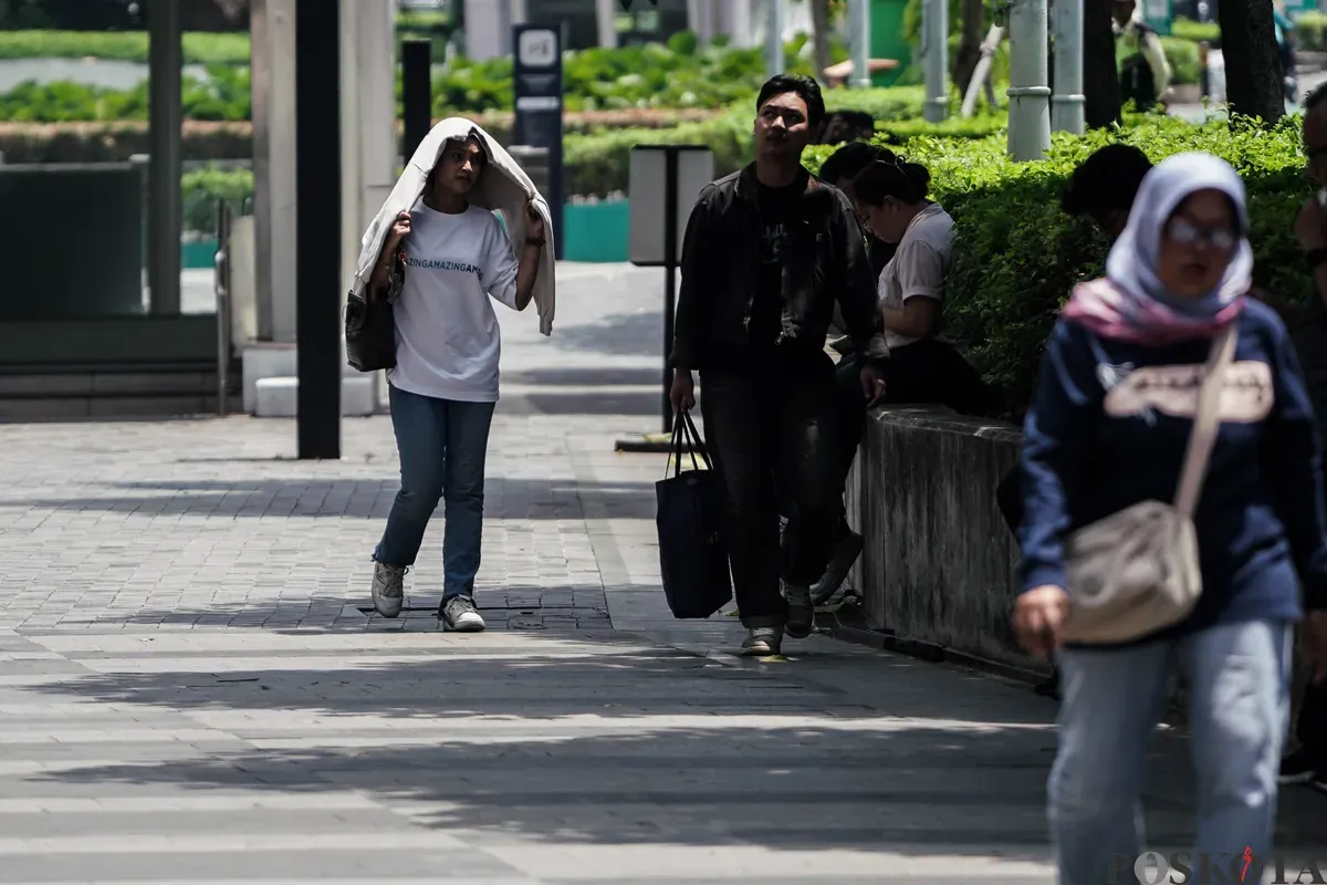Warga berjalan di tengah cuaca terik di Jalan Jenderal Sudirman, Jakarta, Kamis, 16 Oktober 2025. (Sumber: Poskota/Bilal Nugraha Ginanjar)