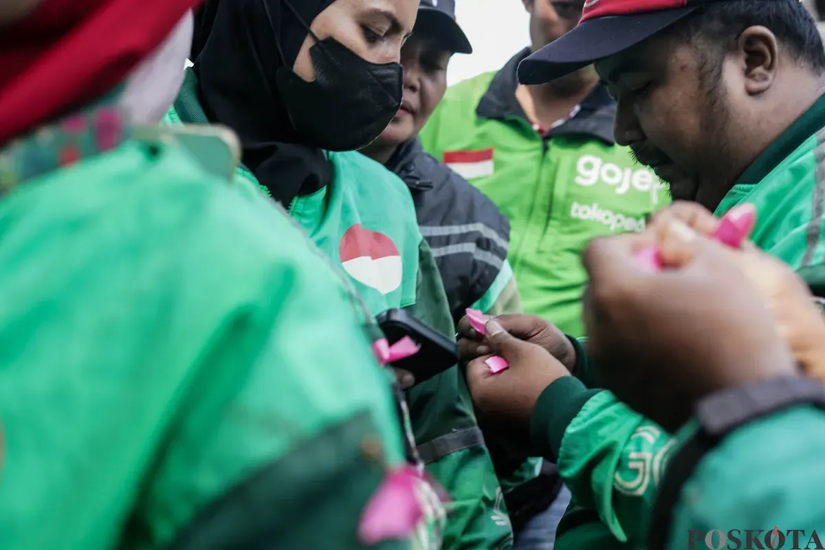 Sejumlah pengemudi ojek daring (ojol) membagikan bunga kepada petugas di kawasan Monumen Nasional, Jakarta, Selasa, 2 September 2025. (Sumber: Poskota/Bilal Nugraha Ginanjar)