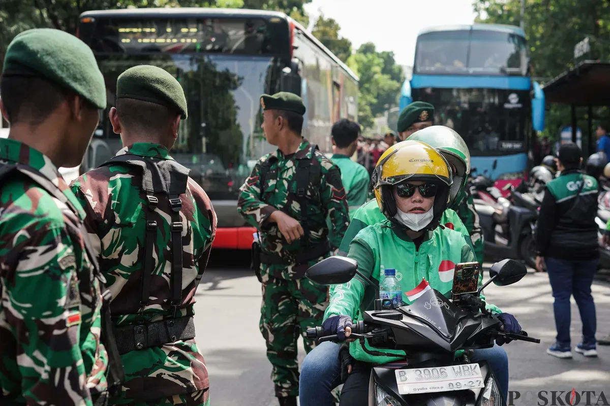 Sejumlah pengemudi ojek daring (ojol) membagikan bunga kepada petugas di kawasan Monumen Nasional, Jakarta, Selasa, 2 September 2025. (Sumber: Poskota/Bilal Nugraha Ginanjar)