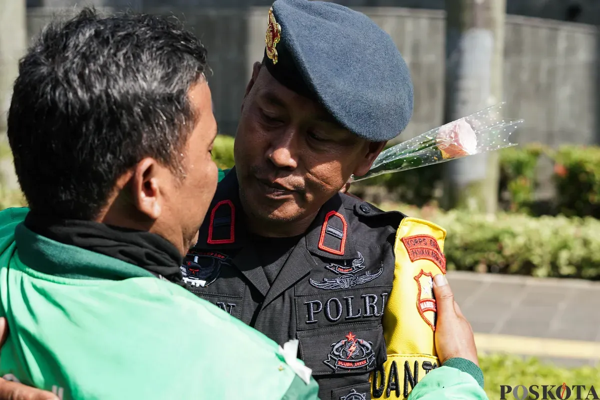 Sejumlah pengemudi ojek daring (ojol) membagikan bunga kepada petugas di kawasan Monumen Nasional, Jakarta, Selasa, 2 September 2025. (Sumber: Poskota/Bilal Nugraha Ginanjar)