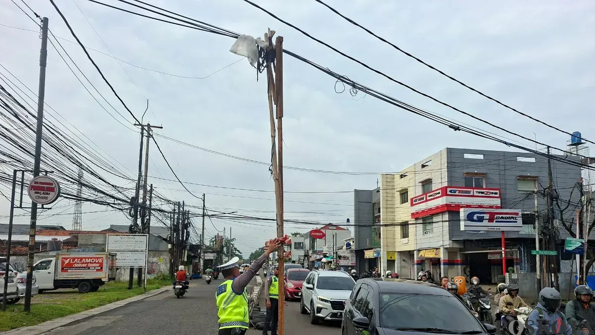 Kabel menjuntai ke jalan raya di Depok ditopang bambu dan kayu. (Sumber: Poskota/ Angga Pahlevi)