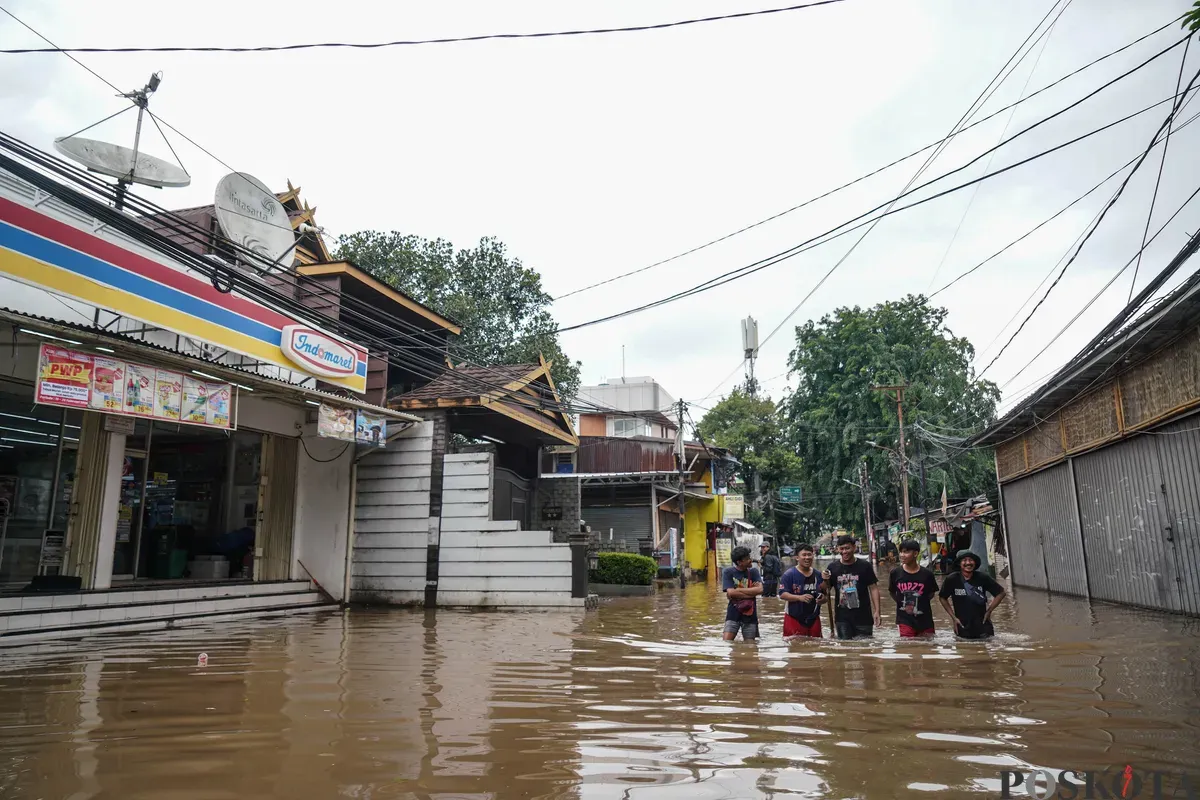 Warga melintasi genangan banjir di Jalan Swadharma Raya, Jakarta Selatan, Jumat, 20 Februari 2026. (Sumber: Poskota/Bilal Nugraha Ginanjar)