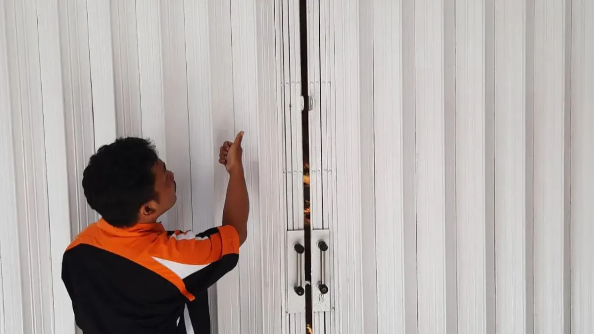 Pegawai toko menunjukkan pintu teralis besi yang dibobol pelaku. (Sumber: Istimewa)