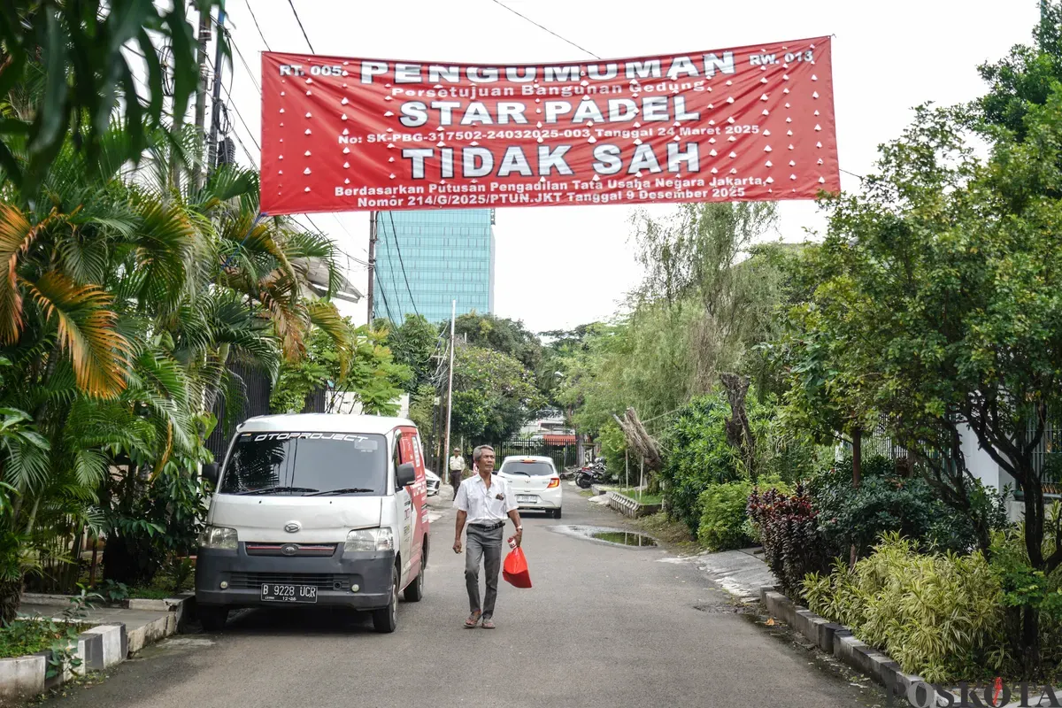 Warga berjalan melewati spanduk penolakan lapangan padel di Jalan Pulomas Barat II, Kayu Putih, Jakarta Timur, Minggu, 22 Februari 2026. (Sumber: Poskota/Bilal Nugraha Ginanjar)