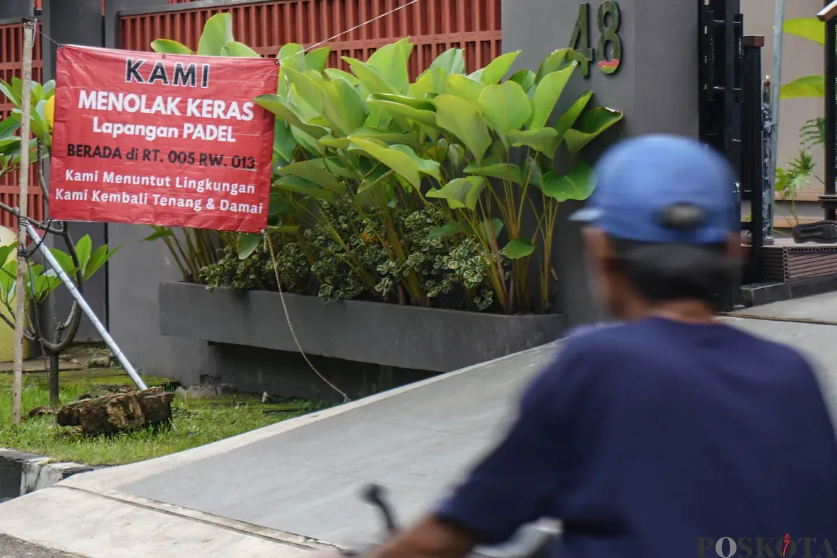 Warga berjalan melewati spanduk penolakan lapangan padel di Jalan Pulomas Barat II, Kayu Putih, Jakarta Timur, Minggu, 22 Februari 2026. (Sumber: Poskota/Bilal Nugraha Ginanjar)