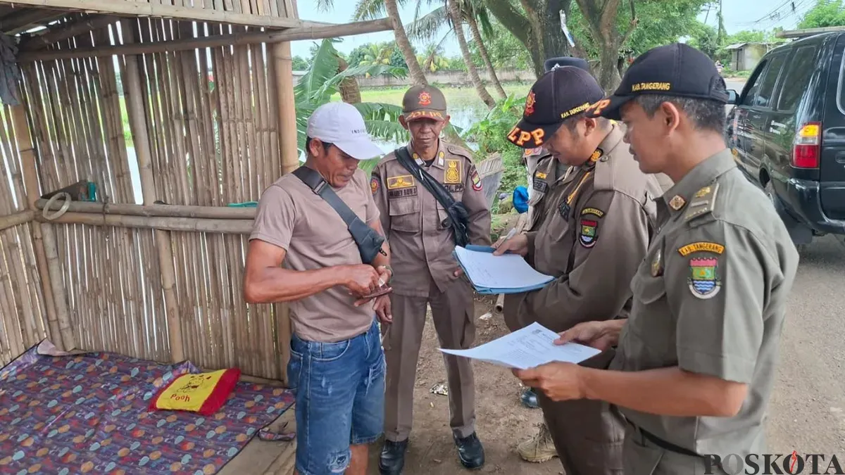 Anggota Satpol PP Kabupaten Tangerang mengirimkan surat peringatan kepada pemilik bangunan liar di Jalan Raya Pakuhaji, Desa Keramat, Kecamatan Pakuhaji, Kabupaten Tangerang. (Sumber: Poskota/Veronica Prasetio)