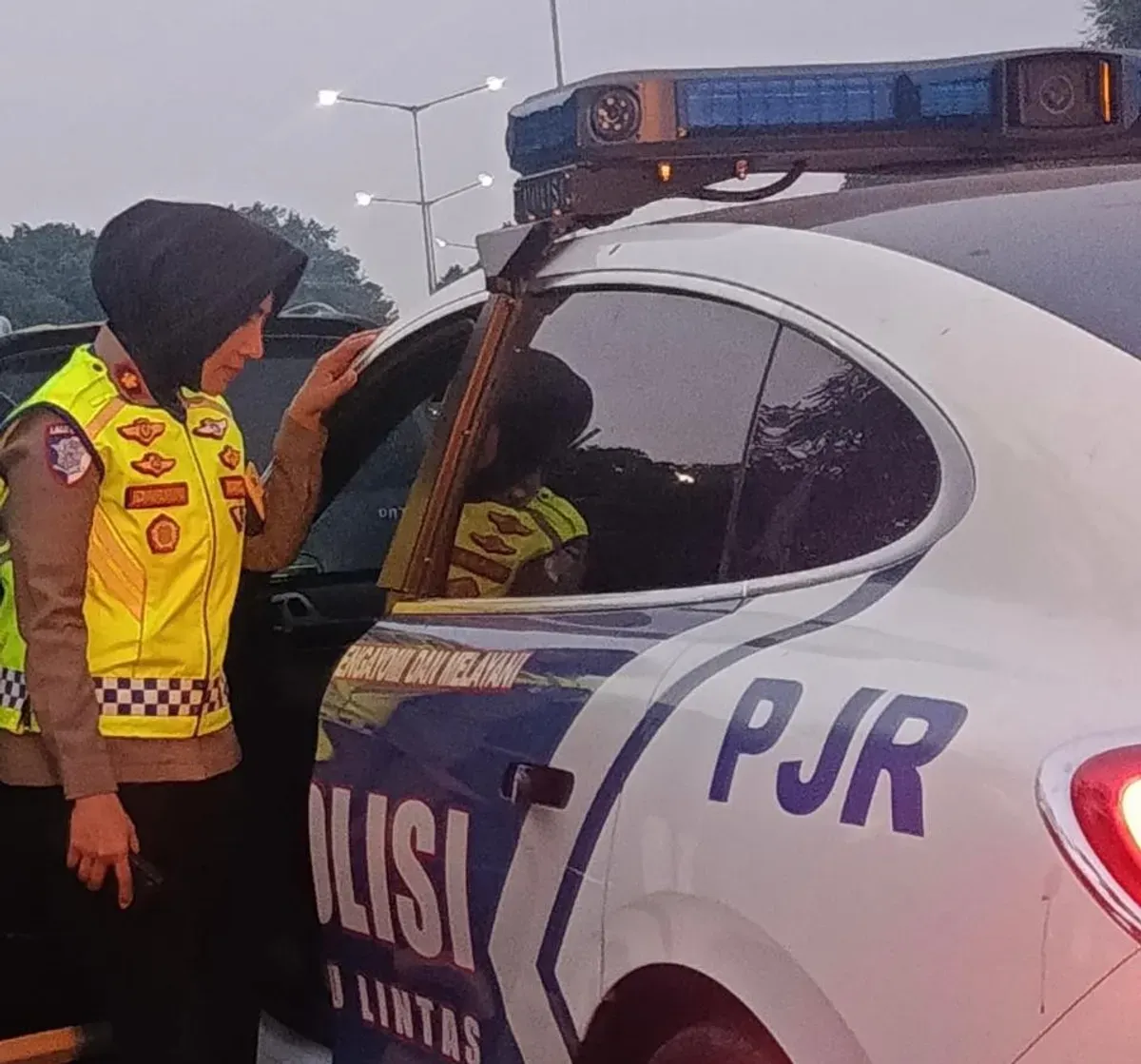 Kompol Darmawati, Kepala Induk PJR BSD Korlantas Polri, membantu mengevakuasi ibu hamil ke mobil patroli setelah kendaraan yang ditumpanginya mengalami overheat di KM 06 Ruas Tol BSD, Senin (13/7/2026). (Sumber: Istimewa)