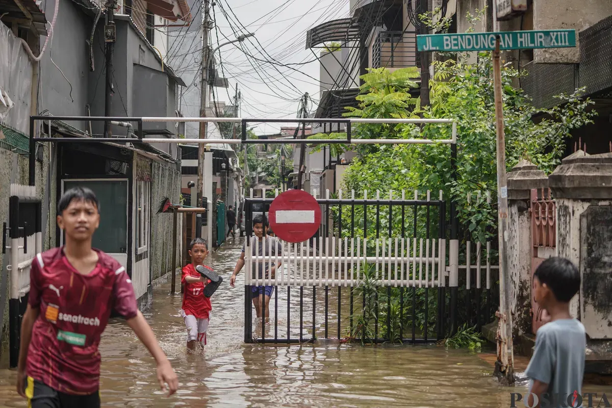 Warga melintasi genagan banjir di Jalan Bendungan Hilir, Jakarta Selatan, Minggu, 8 Maret 2026. (Sumber: Poskota/Bilal Nugraha Ginanjar)