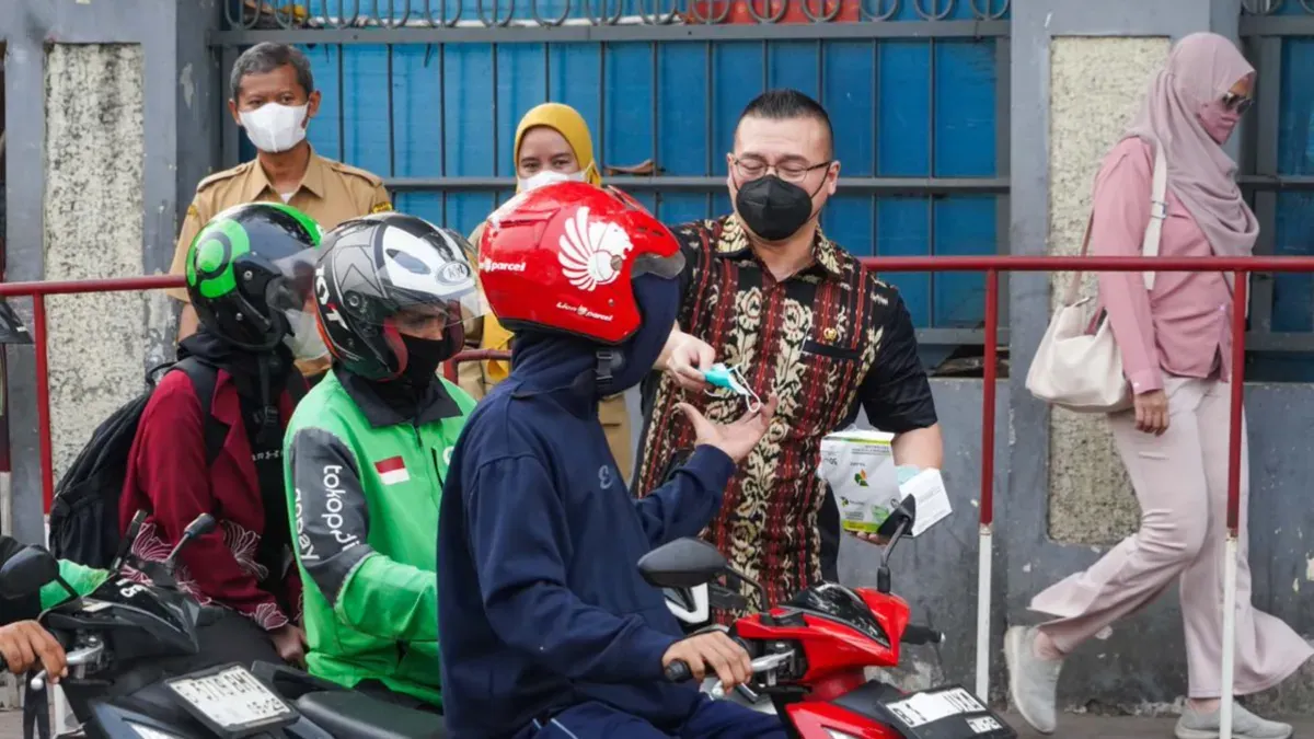 Anggota Komisi C DPRD DKI Jakarta, Hardiyanto Kenneth saat membagikan masker kepada pengendara motor dan pejalan kaki di Latumenten, Jakarta Barat. (Sumber: Istimewa)