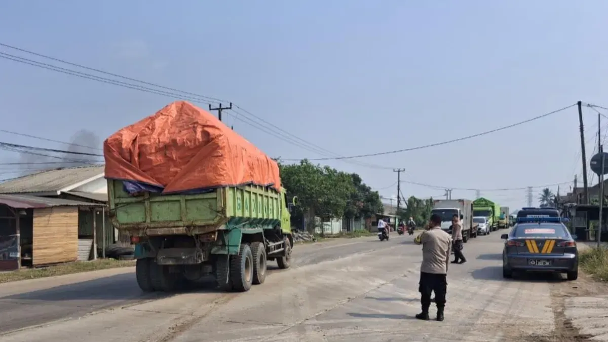 Petugas Polsek Jawilan mengarahkan kendaraan dump truk yang parkir di bahu jalan untuk mengisi kantong-kantong parkir. (Sumber: Polsek Jawilan)