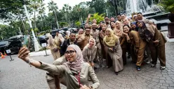 Sejumlah ASN Pemerintah Provinsi DKI Jakarta berswafoto bersama di halaman Balai Kota Jakarta pada hari pertama masuk kerja usai libur Lebaran 2025. (Sumber: Poskota/Bilal Nugraha Ginanjar)
